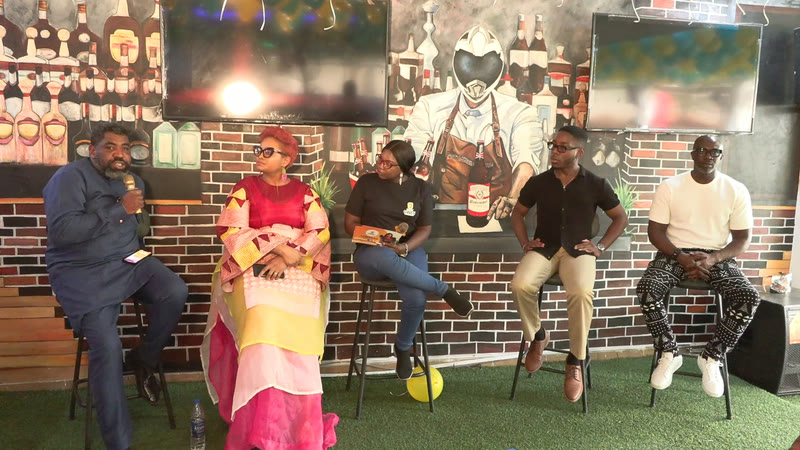 Five panellists seated on stools in front of a brick wall, sharing their experiences