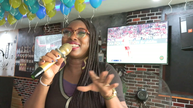 A member speaking into a microphone under green and yellow balloons