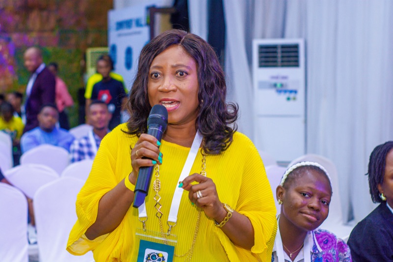 An attendee in yellow asking a question into a microphone
